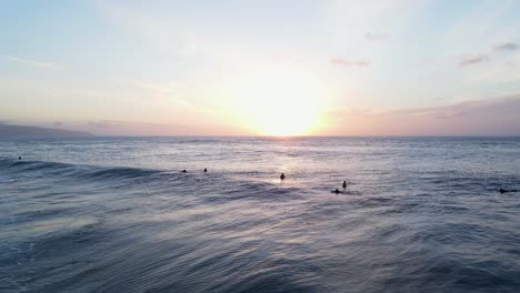 surfers at sunset on the waters of north shore in oahu, hawaii, wide shot