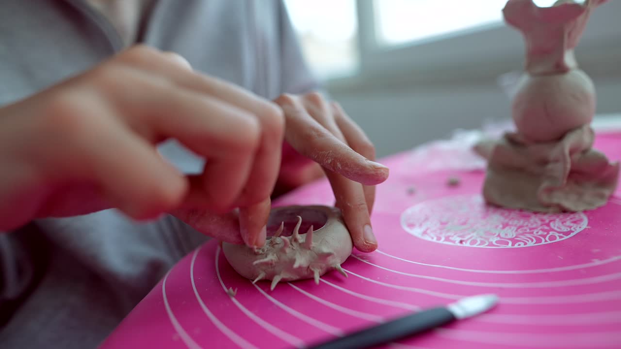 Primo piano di mani che scolpiscono un oggetto di argilla con punte