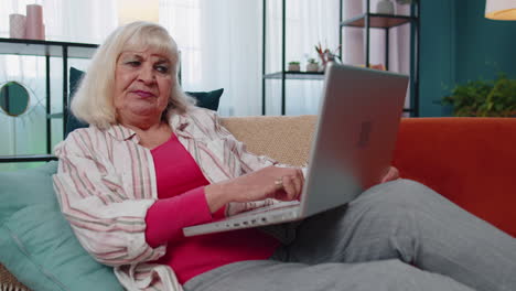 Stressed-upset-senior-grandmother-woman-working-on-laptop-computer,-received-bad,-loss-news-at-home