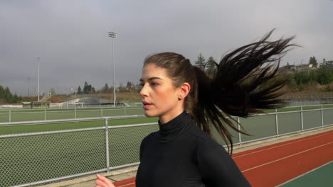 young beautiful sporty woman running on the track, slow motion follow