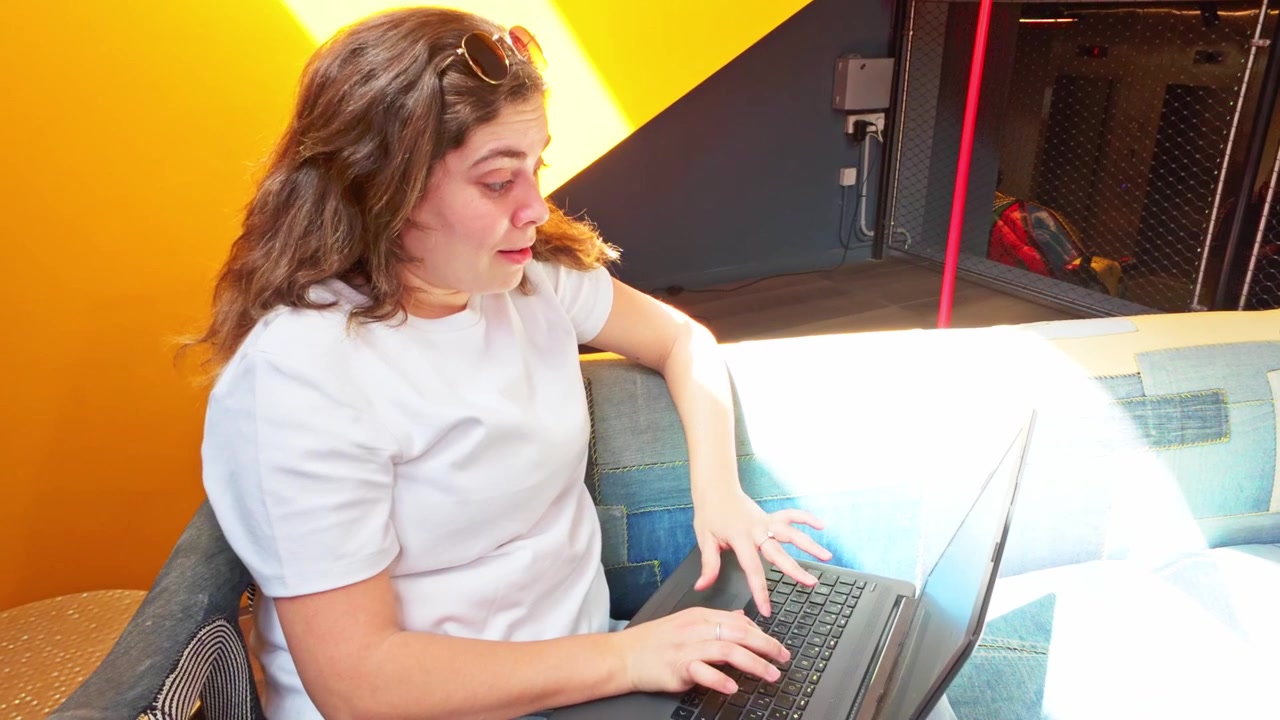Frau arbeitet am Laptop in einer modernen Coworking-Lobby