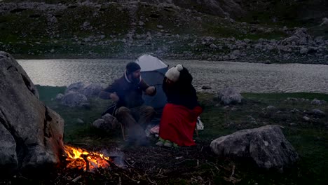 pareja de viajeros al anochecer cerca de un fuego de campamento
