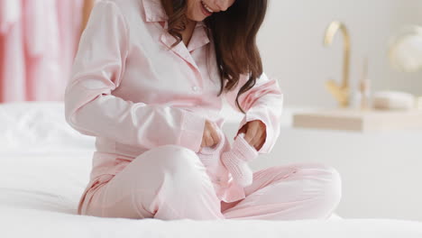 pregnant woman in pink pajamas with baby socks