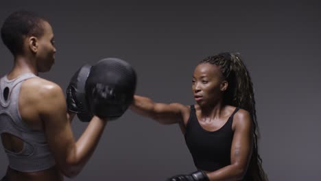 fotografía de estudio de una mujer con guantes de boxeo luchando con el entrenador 4