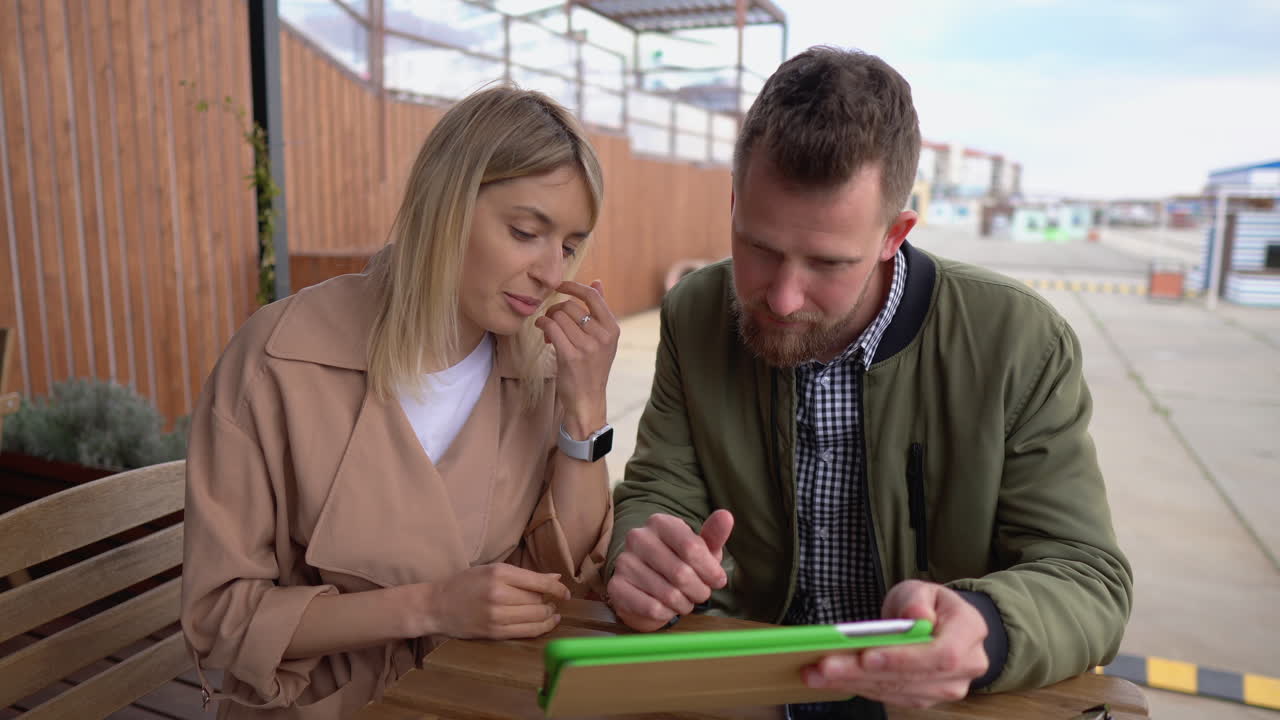 pareja discutiendo en la tableta en un café al aire libre