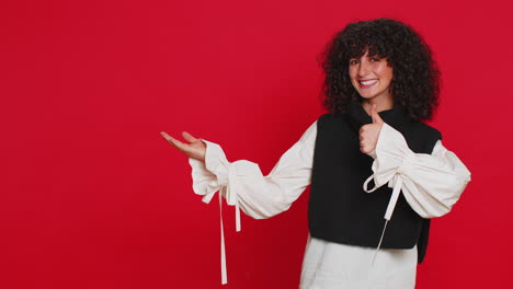 young woman showing thumbs up and pointing at left on blank space place for your advertisement logo