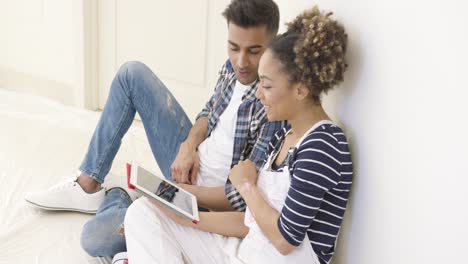 una pareja guapa se sienta y usa una tableta