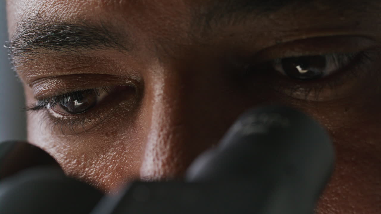 Eyes of Concentrated Scientist Examining Sample through Microscope