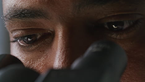 eyes of concentrated scientist examining sample through microscope