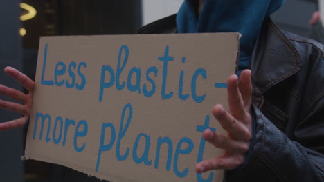 close up of a young male activist holding a cardboard placard against the use of plastic during a climate change protest 1