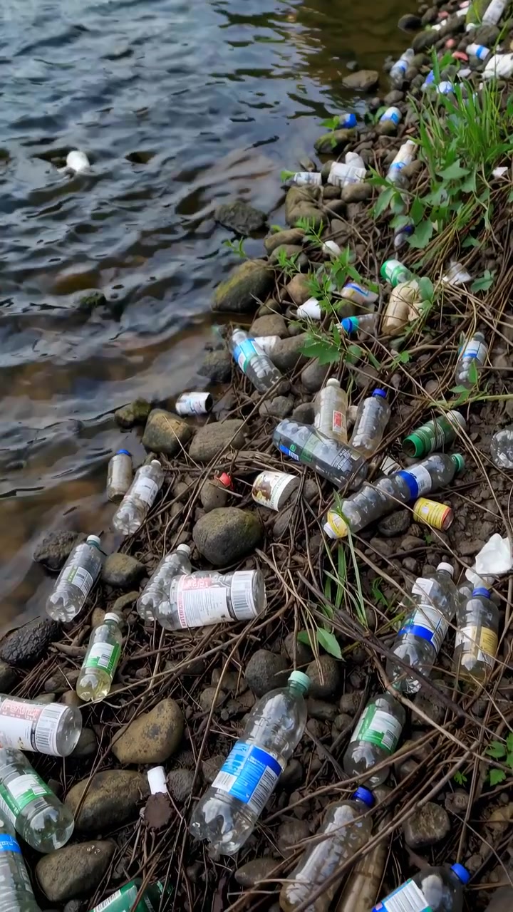 Rifiuti di plastica che inquinano la sponda del fiume e il corso d'acqua