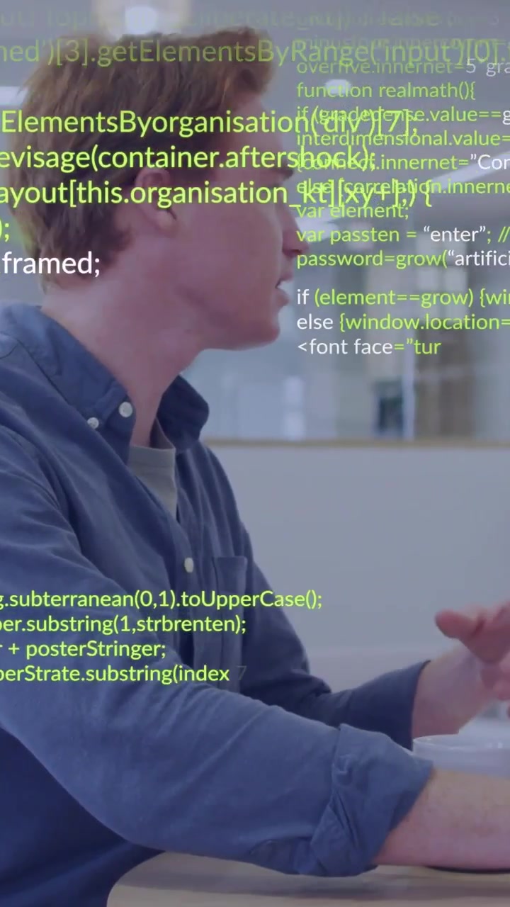 Vertical video: Male dev typing on laptop in office while green code overlaying and collaborating