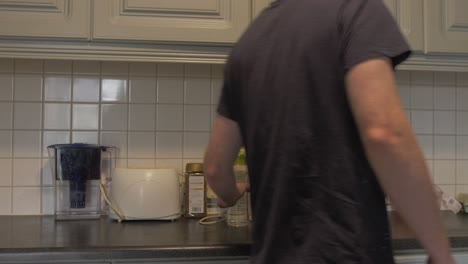 man places water bottle on kitchen counter with prepared lunchbox