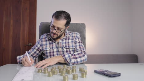 Man-counting-coins-doing-accounting-writes-down-numbers-on-a-paper