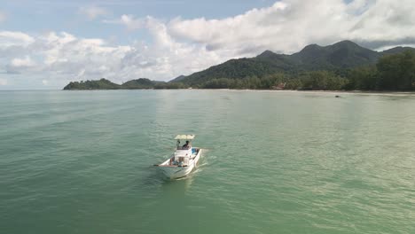 small-fishing-motor-boat-of-the-coast-of-Thai-tropical-island-with-mountains,-blue-sky