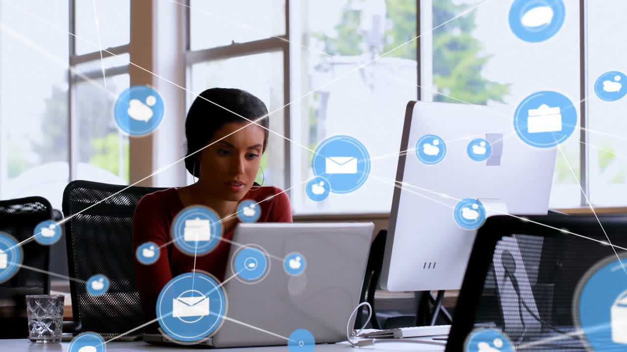 Animazione di rete di connessioni con icone su imprenditrice birazziale che usa il laptop in ufficio