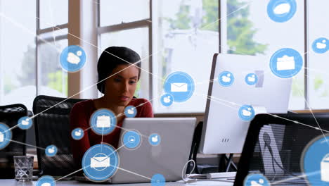 animation of network of connections with icons over biracial businesswoman using laptop in office