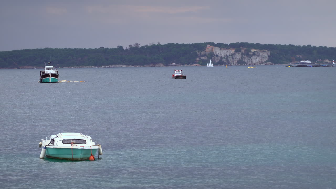 Multiple boats floating on the sea on a cloudy day