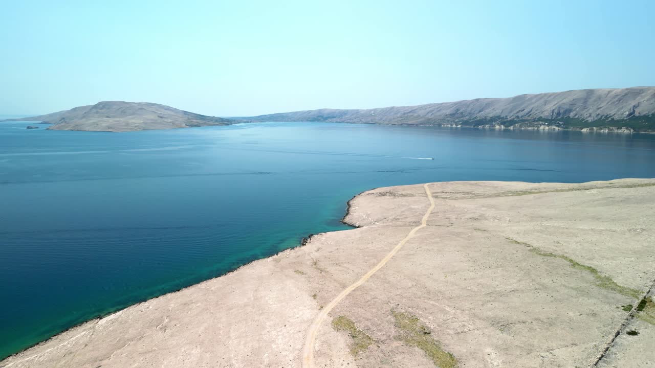 Clear blue sky and deep blue Adriatic Sea with white stoney island road from above, Pag, Croatia in summer heat