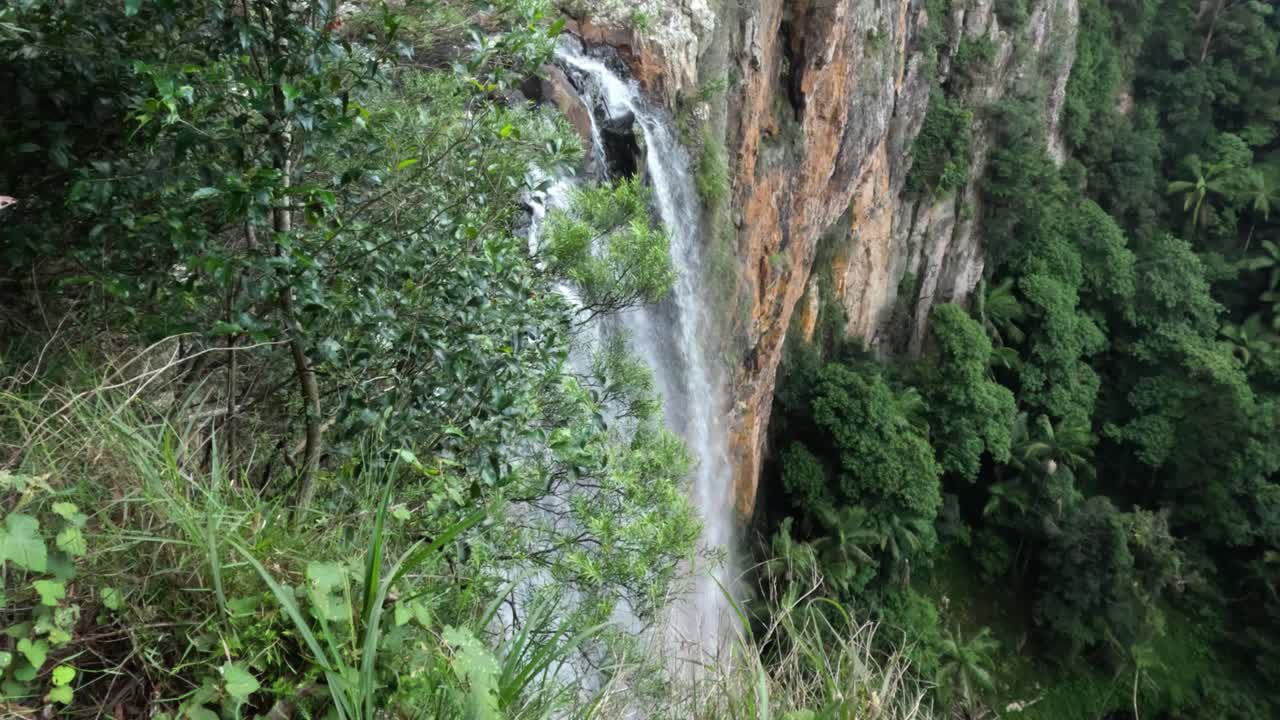 una cascada que fluye a través de un acantilado de bosque verde
