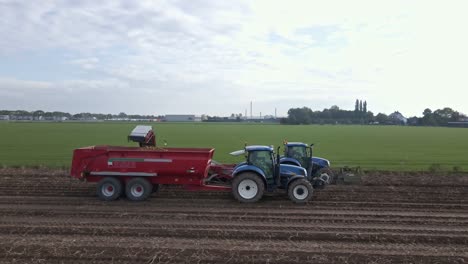 Aerial-of-farmers-in-tractors-harvesting-potato-Sideview