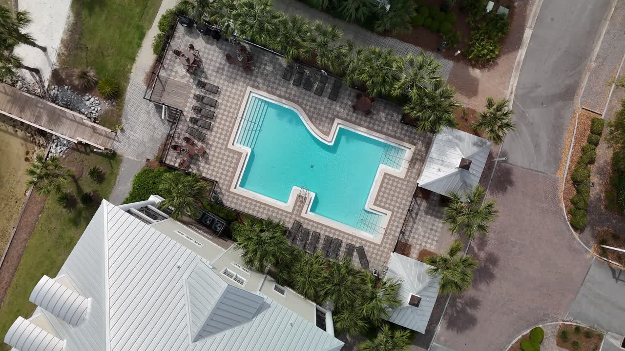 Top-down rapid spiral drone movement of residential pool area surrounded by palm trees and local buildings, Panama City Beach, Florida, USA