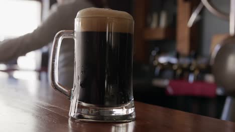 hands of a caucasian man serving a pint of beer at a microbrewery pub