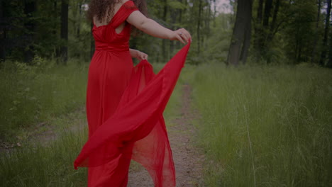 woman in red dress walkin in forest