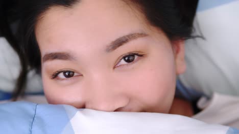 웃 고 카메라를 보고 여성의 근접 촬영 및 담요로 덮여 침대에 사랑 스러운 거짓말
