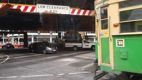 tram and vehicles navigating intersection under bridge