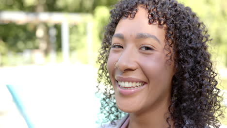 smiling woman with curly hair enjoying sunny day by swimming pool outdoors