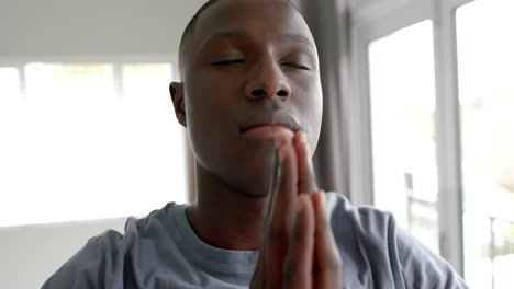 African-american-man-doing-yoga-and-meditating-at-home,-slow-motion