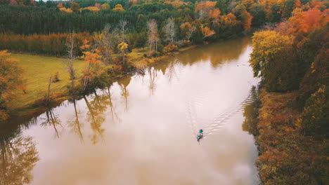 Gorgeous-aerial-footage-of-the-colorful,-autumn-foliage-along-a-river-on-a-calm,-October-day