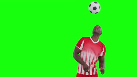 Video-Eines-Afroamerikanischen-Männlichen-Fußballspielers,-Der-Den-Ball-Auf-Grünem-Hintergrund-Mit-Dem-Kopf-Kickt