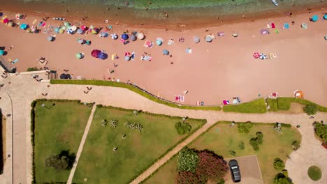 Beachgoers-Relaxing-On-The-Sveti-Stefan-Beach-With-Parasol-And-Sun-Loungers-In-Summer