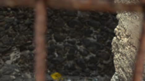 Looking-through-tiled-metal-ground-grid,-rack-focus-to-black-rocks,-spooky