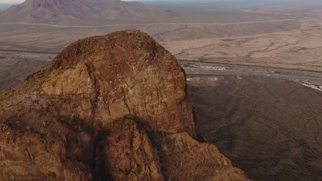 aerial drone footage over sunlit mountain formations in sonoran desert in tucson arizona, sunset on picacho peak