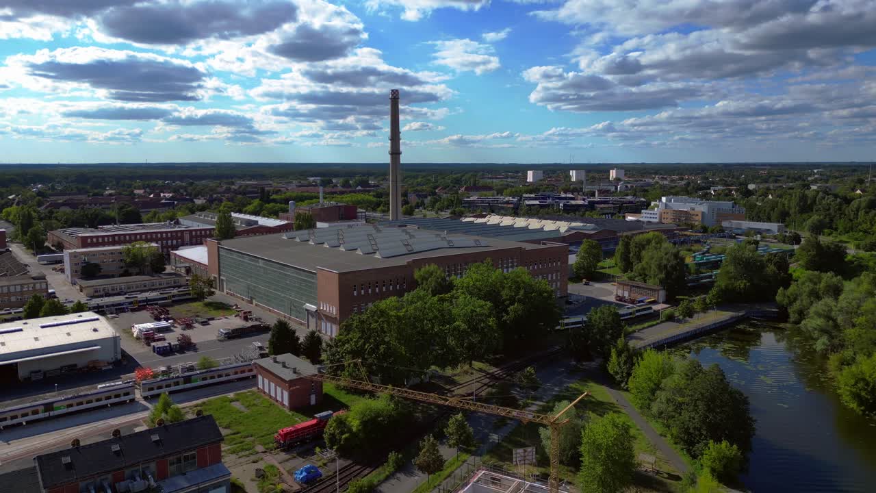 industrial buildings and a chimney in Hennigsdorf, Germany, with a train passing by. Fabulous aerial view flight speed ramp hyper motion time lapse fly push forward drone