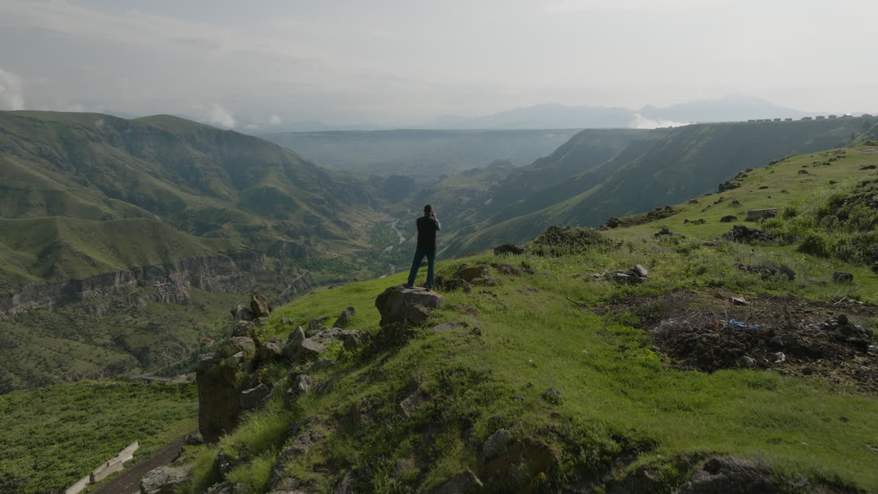 조지아의 녹슨 급수탑 근처에 서서 아름다운 산 풍경 사진을 찍는 자연 사진작가