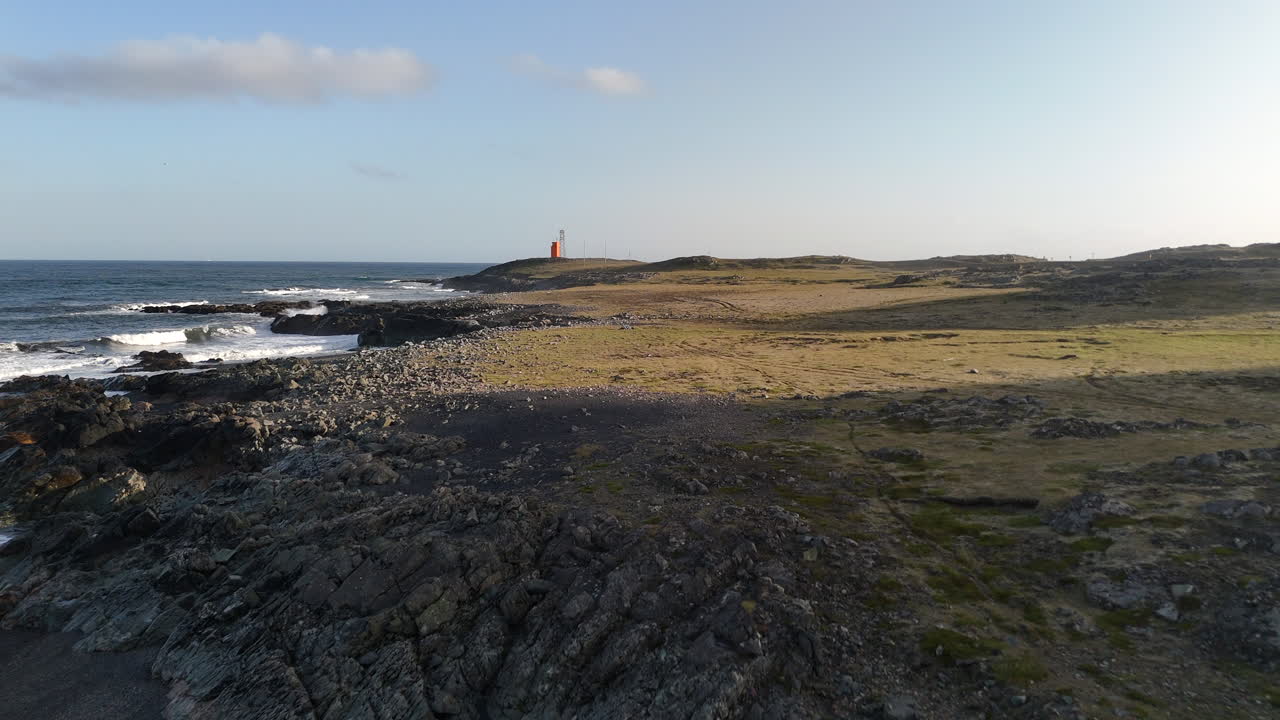 Luftfoto af et højt islandsk bjerg omgivet af skyer ved solnedgang, der fremhæver dramatiske skråninger og varme aftentoner hen over et robust terræn