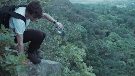 Junger-Mann-Springt-Von-Einem-Felsen,-Der-In-Der-Wildnis-Sitzt