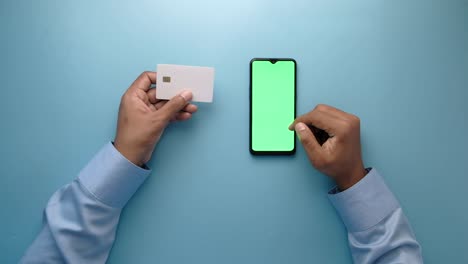 hombre con una tarjeta de crédito en la mano y usando un teléfono inteligente para comprar en línea