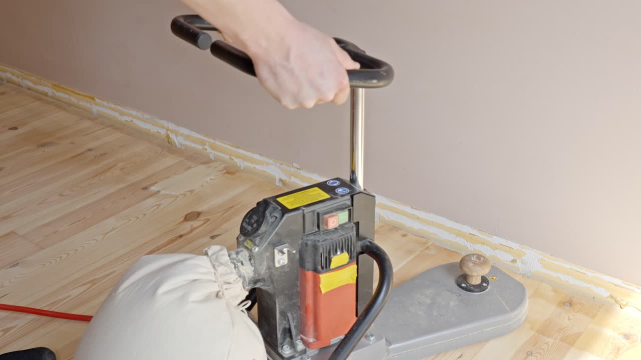 Sanding wood floor edges using a professional tool to smooth the surface