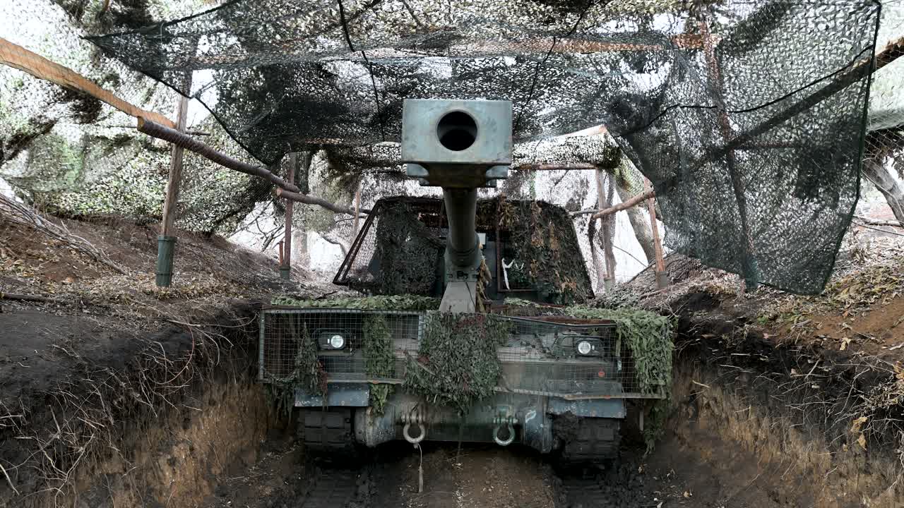 A menacing view down the barrel of a Ukrainian PzH 2000 self-propelled howitzer. The German-made artillery is hidden in a fortified position, ready for a fire mission