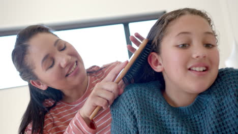 Feliz-Madre-Birracial-Cepillando-El-Cabello-De-Su-Hija-En-Un-Dormitorio-Soleado