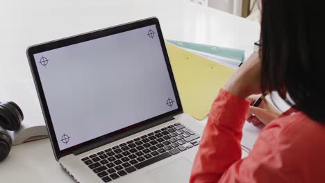 Video-Einer-Gemischtrassigen-Frau-Mit-Dunklem-Haar,-Die-Einen-Laptop-Mit-Leerem-Bildschirm-Benutzt