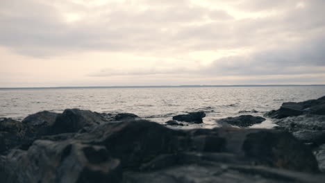 low angle view of small waves hitting cliffs, on a rocky shore, on a moody, cloudy autumn day, in finland