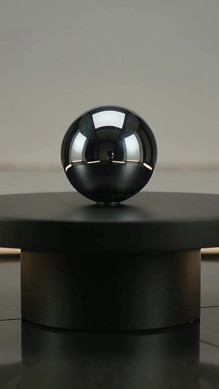 Video verticale: Il cambiamento di luce fa oscillare una sfera lucida, che gira su un tavolo da studio, con base opaca
