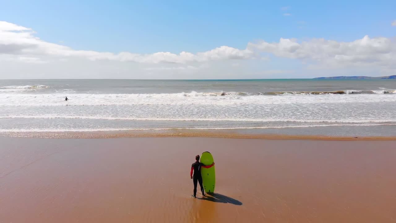 surfista masculino de pie con una tabla de surf en la playa en un día soleado 4k