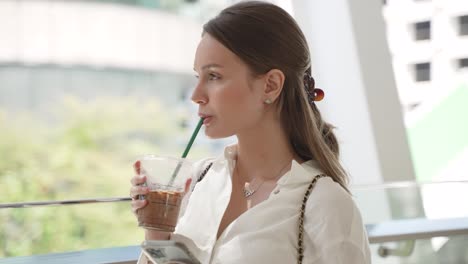 mujer bebiendo café y usando el teléfono en un centro comercial
